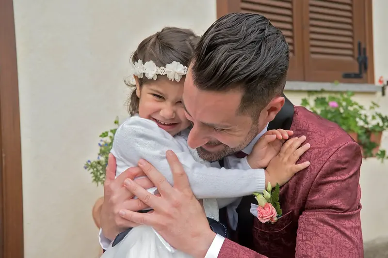 Una bambina con la coroncina di fiori abbraccia il papà